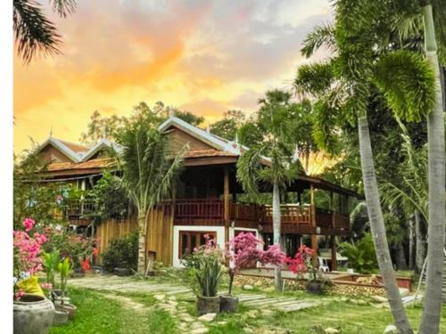 una casa con palmeras delante en Devi Kampot Resort at Phum Kampot, en Kampot