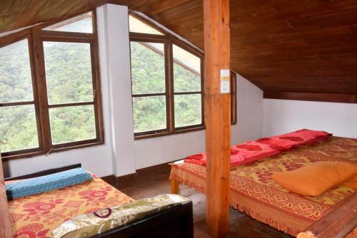 a bedroom with two beds and two windows at Forest View Villa (Bangalahatha) in Nuwara Eliya