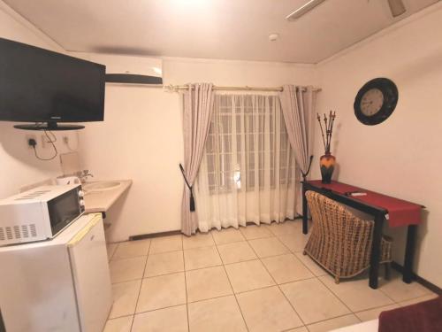 eine Küche mit einer Mikrowelle, einem Tisch und einem Fenster in der Unterkunft Rose Guest House in Pretoria