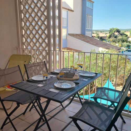 une table noire et des chaises sur un balcon dans l'établissement Appartement T2 climatisé, 4 couchages, Les Balcons de la Méditerranée, à Narbonne-Plage