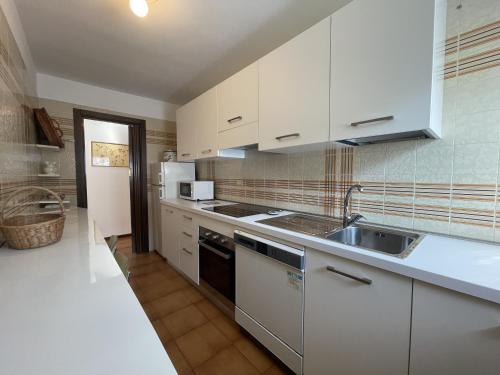 ピンツォーロにあるAppartamenti Residenza Alpinaの白いキャビネットとシンク付きのキッチン