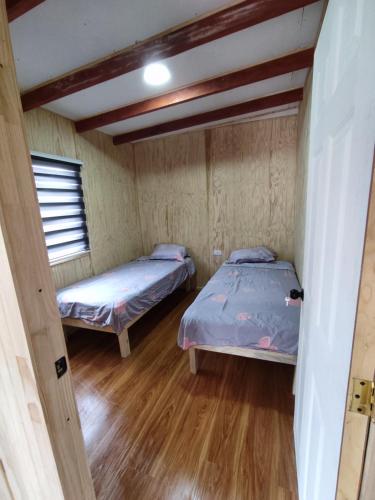 Duas camas num pequeno quarto com pisos em madeira em CABAÑA pasos de la playa panguipulli em Panguipulli