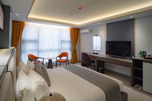 una camera d'albergo con letto, scrivania e TV di Subic Riviera Hotel & Residences a Kababae