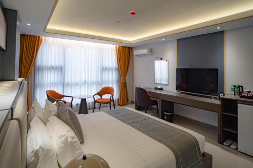 a hotel room with a bed and a desk and a television at Subic Riviera Hotel & Residences in Kababae