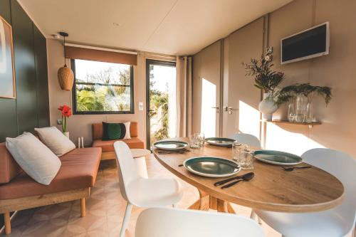 a dining room with a wooden table and white chairs at Camping de la côte des légendes in Brignogan-Plages