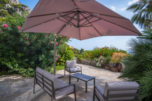 een patio met 2 stoelen, een tafel en een parasol bij Villa Sterlizia in Capri