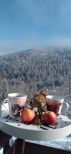 two cups and two apples on a table with a view at Planinska kuća ,,Furtula" Jahorina in Pale