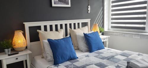 ein Schlafzimmer mit blauen und weißen Kissen auf einem Bett in der Unterkunft VILLA NORTH Apartament in Jastrzębia Góra