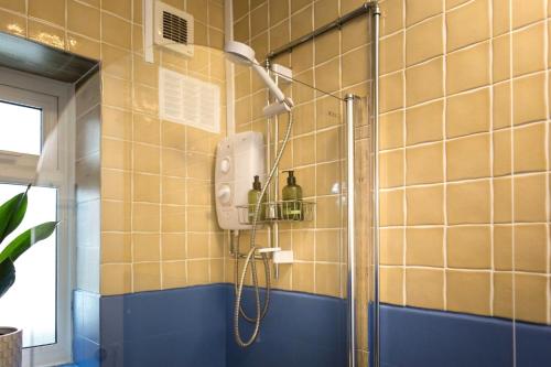 a shower in a bathroom with yellow tiles at Sea Downs - moments from beach in Eastbourne