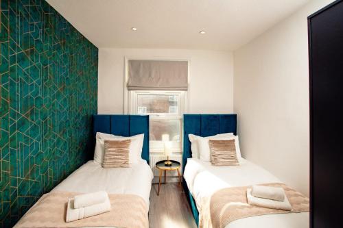 Duas camas num quarto com paredes azuis e brancas em Modern 3 and 2 bedroom apartment in Maida Vale em Londres