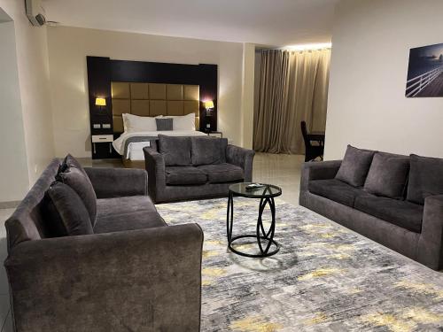 a living room with two couches and a bed at Rollace Hotel in Ikeja