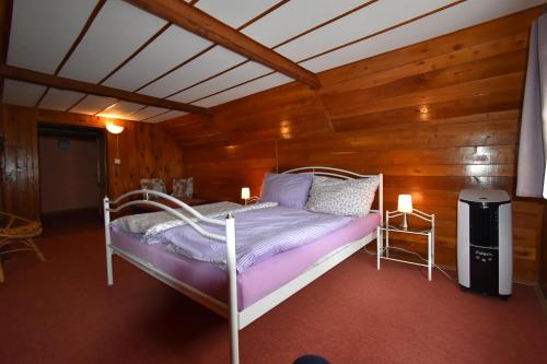 a bedroom with a bed in a room with wooden walls at Chalupa Alexandra in Kacanovy