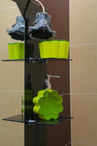 a shelf in a bathroom with green cups and a faucet at BOUZNIKA 75 in Bouznika