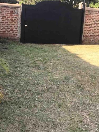 a black gate in a yard with a brick wall at KareBer Deluxe - Gulu - Uganda in Gulu
