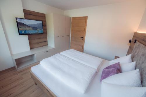 a bedroom with a white bed and a tv on the wall at Apart Eder in Schwendau
