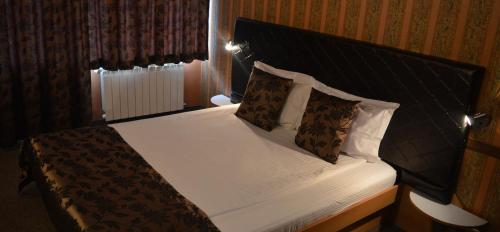 Schlafzimmer mit einem Bett mit weißer Bettwäsche und Kissen in der Unterkunft Family Hotel Yagoda88 in Sofia