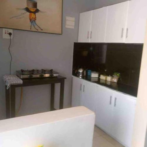 a kitchen with white cabinets and a counter top at KareBer Deluxe - Gulu - Uganda in Gulu