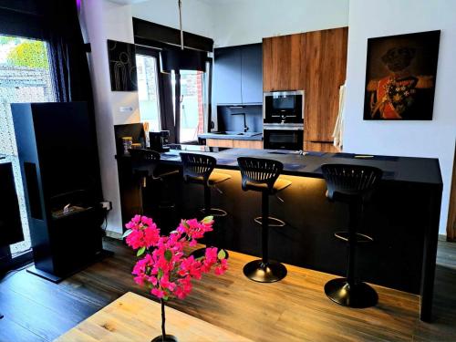 una cocina con barra con taburetes y flores rosas en petite chambre dans une jolie colocation, en Lieja