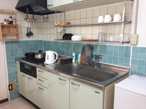 een keuken met een roestvrijstalen wastafel en blauwe tegels bij INARI - Vacation STAY 87349 in Takamatsu