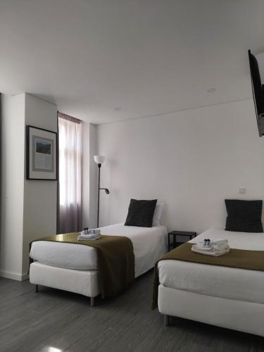 a hotel room with two beds and a window at OH Studios Lousã in Lousã