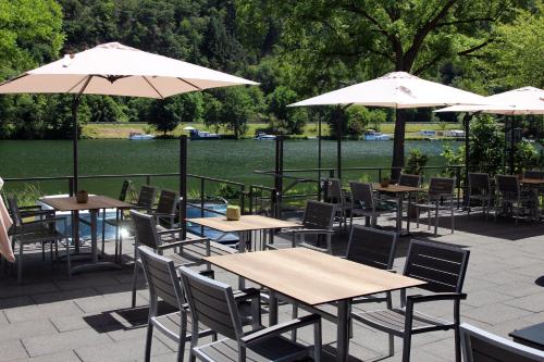 a patio with tables and chairs and umbrellas at Uferdeck - Boutique Hotel in Traben-Trarbach