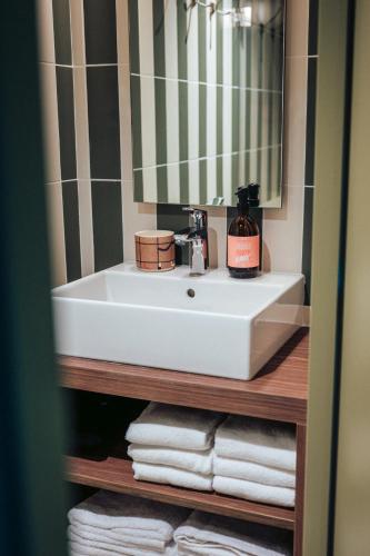 a bathroom with a sink and a mirror and towels at JOST Hotel Montpellier Centre St Roch in Montpellier