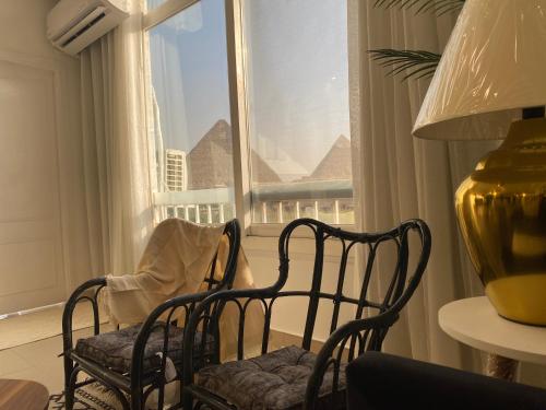a living room with two chairs and a window at The Pyramid Area Vibe in Cairo