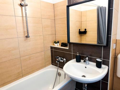 a bathroom with a sink and a tub and a mirror at Modernes Apartment Nähe Chemnitz in Neukirchen