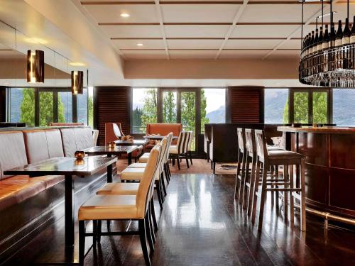 a restaurant with tables and chairs and a bar at Hotel St Moritz Queenstown - MGallery by Sofitel in Queenstown