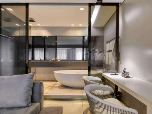 a bathroom with a tub and two chairs and a sink at Mercure Belo Horizonte Vila da Serra in Belo Horizonte