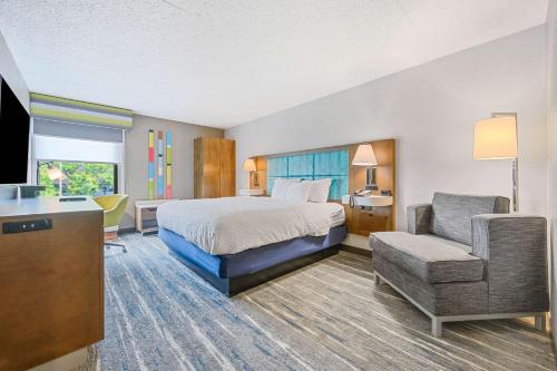 a hotel room with a bed and a chair at Hampton Inn St. Louis - Westport in Maryland Heights