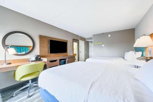 a hotel room with a bed and a desk and a tv at Hampton Inn St. Louis - Westport in Maryland Heights