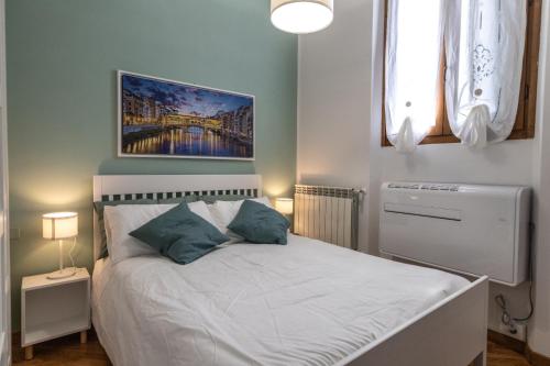 Un dormitorio con una cama blanca con almohadas azules. en Casa Barco Firenze, en Florencia