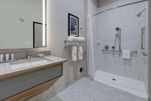 a white bathroom with a sink and a shower at The Elm, a Ramada by Wyndham in Little Elm