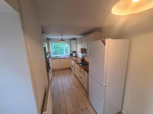 a kitchen with a white refrigerator and a wooden floor at L & J Escapes - 8 Bedrooms suitable for Contractors and Families- Private parking available for 6 vehicles in Coseley