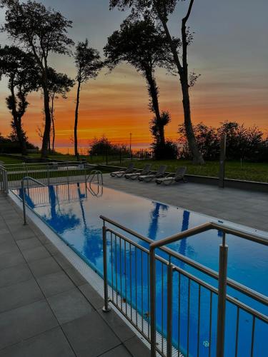 a swimming pool with a sunset in the background at Apartamenty The View Hevenia in Rewal