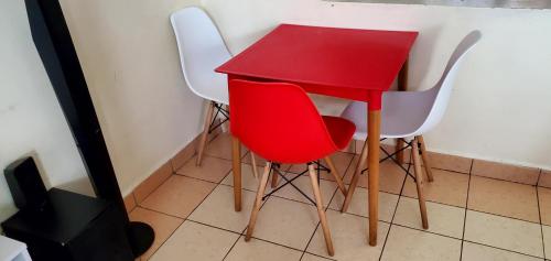 a red table and four white chairs in a room at 2 Bedroom Apartment in Langata in Nairobi