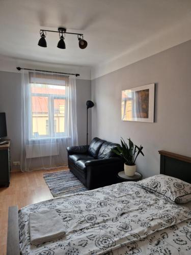 een slaapkamer met een bed en een zwarte leren bank bij Artilerija's apartment in Rīga