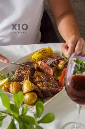 a person cutting a plate of food with a glass of wine at XIO Apartments in Bar