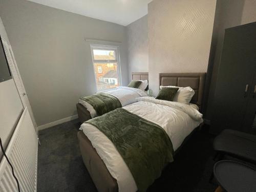 2 camas en una habitación pequeña con ventana en Lovely 4 bedroom Victorian house with back courtyard, en Stoke on Trent