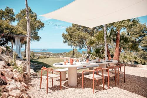 una mesa y sillas blancas bajo una sombrilla blanca en Blue Hill House, King-of-Hill Villa with amazing scenery, sunset & sea view, en San José