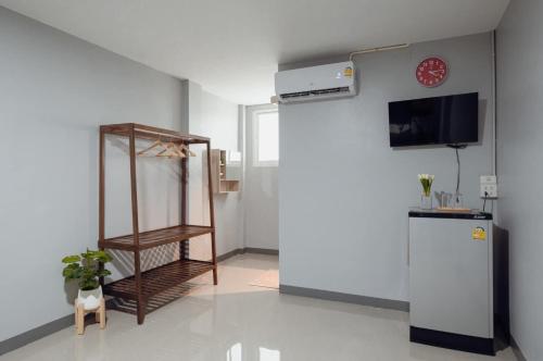 a room with a refrigerator and a clock on the wall at มาดีดี รีสอร์ท in Suphan Buri