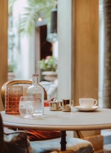 a table with a bottle and cups on it at Cobergher Hotel in Kortrijk