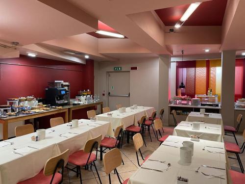 a restaurant with white tables and chairs and a kitchen at Art & Hotel Aeroporto in Stezzano