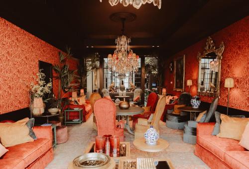 a living room with red walls and furniture and a chandelier at Cobergher Hotel in Kortrijk