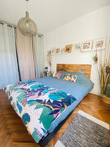 een slaapkamer met een bed met een kleurrijk dekbed bij Évasion Tropicale - Villa d'Artiste avec Jacuzzi Privé dans un jardin Exotique in Mérignac