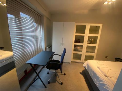 um quarto com uma secretária, uma cama, uma secretária e uma cadeira. em Lovely bright double room very central em Londres