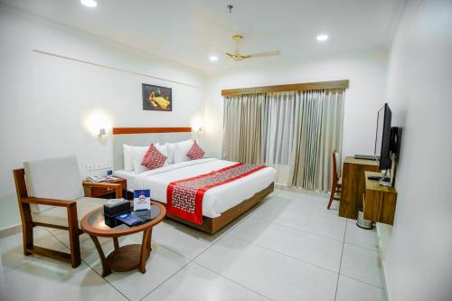 a bedroom with a bed and a table and a tv at KKM INTERNATIONAL in Trivandrum