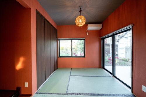 an empty room with orange walls and a chandelier at 大型貸切別荘 HOUSE ASA 最大22名 サウナ BBQ ホームカラオケ 焚き火 from九十九里海岸歩7分 in Kujukuri