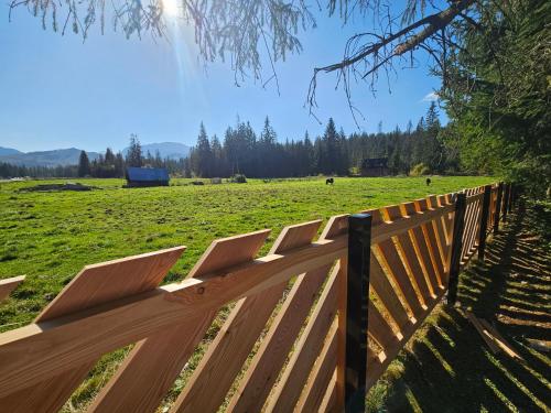 a wooden fence with a field in the background at Domek drewniany Szafran in Witów
